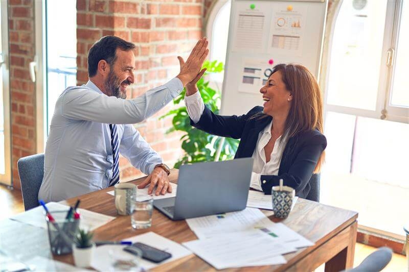 A woman and a man clapping in an office